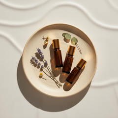 Amber essential oil roller set with botanical sprigs on a warm cream surface