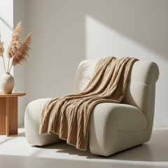 Warm oat-beige ribbed throw folded on a cream lounge chair